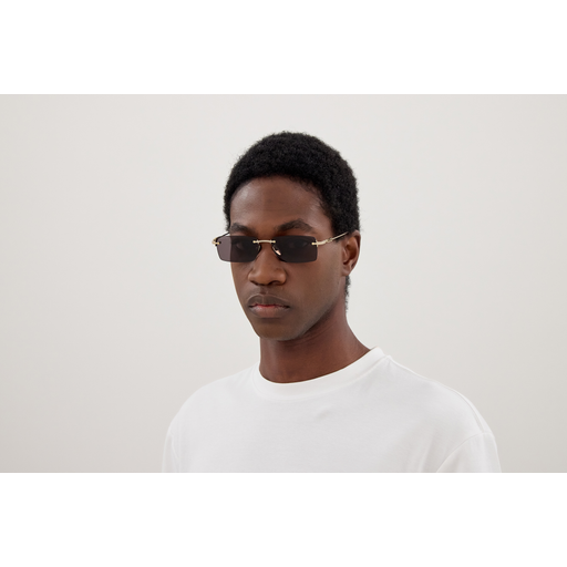 Person wearing sunglasses and a white shirt against a plain background