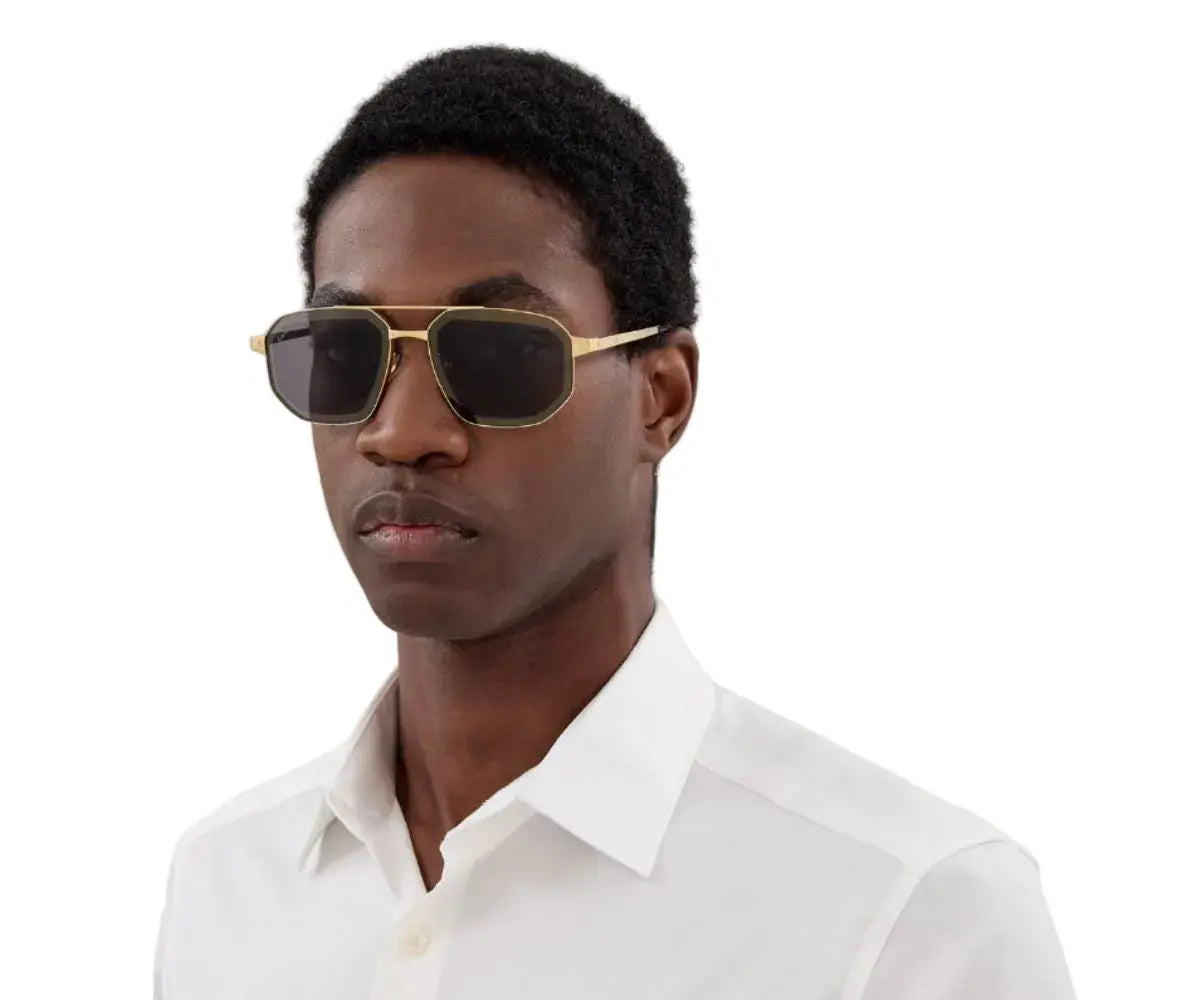 Man wearing gold-framed sunglasses and a white shirt on a white background