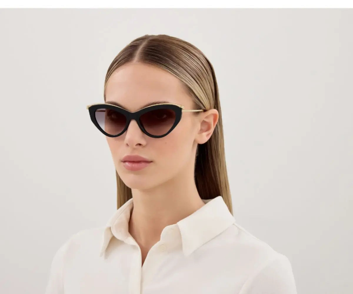 Woman wearing black cat-eye sunglasses against a light gray background