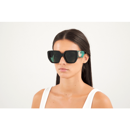 Woman wearing black sunglasses with a brand logo on a white background
