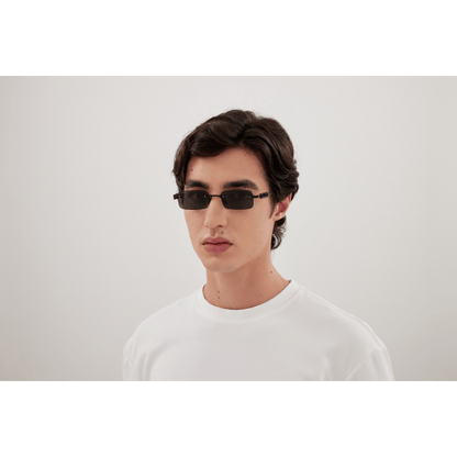 Man wearing sunglasses and a white shirt against a plain background