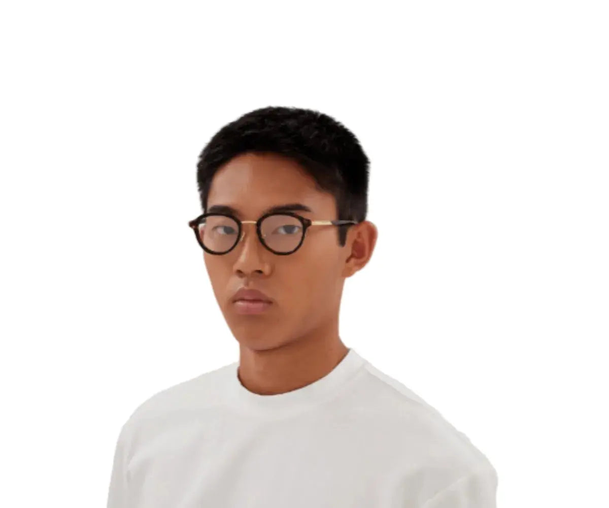 Person wearing glasses and a white shirt on a plain background