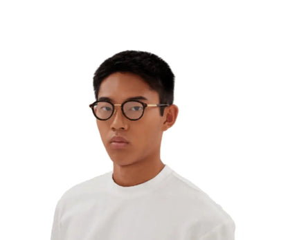 Person wearing glasses and a white shirt on a plain background