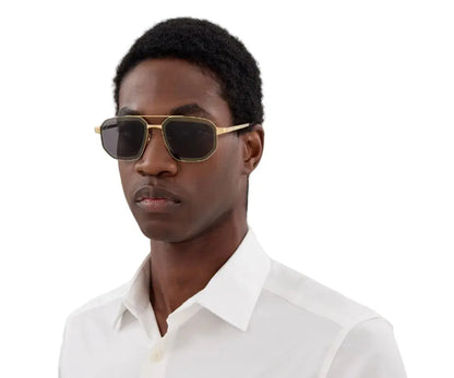 Man wearing gold-framed sunglasses and a white shirt on a white background