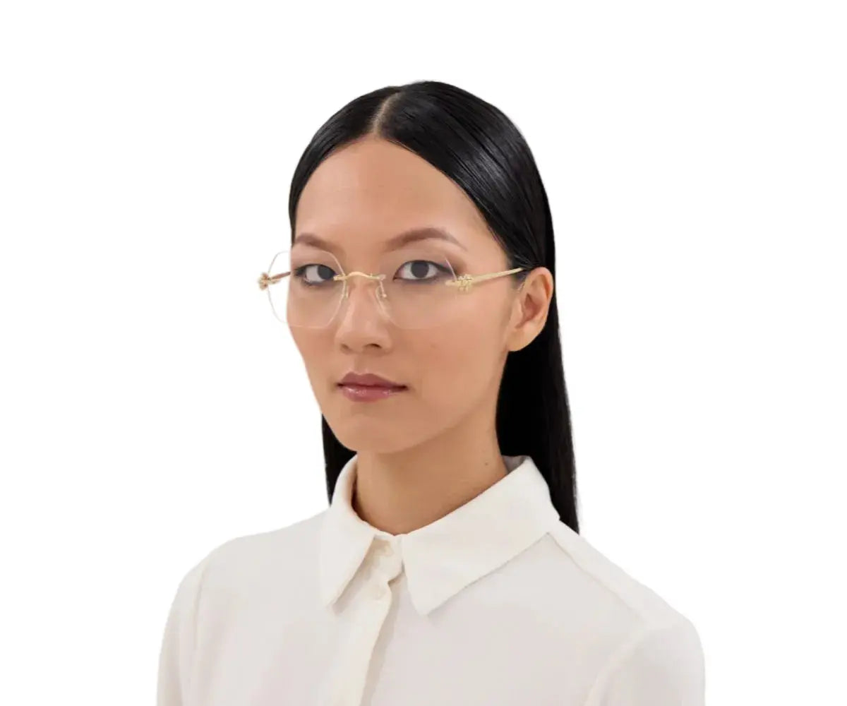 Woman wearing gold-framed glasses and a white shirt on a white background